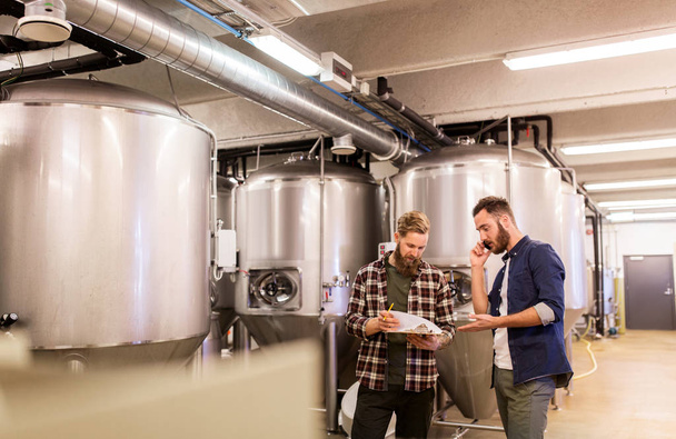 men working at craft brewery or beer plant - Foto, afbeelding