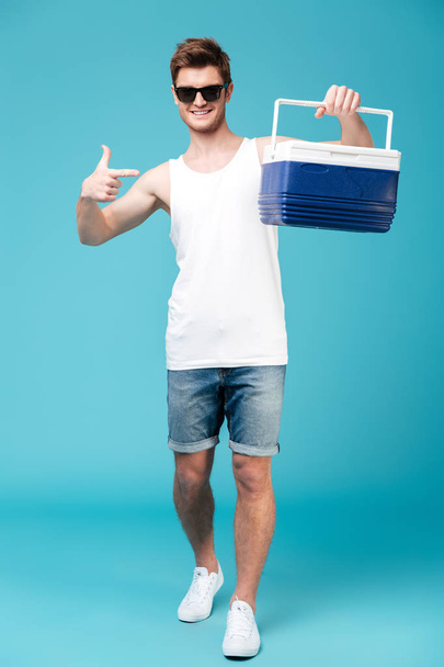 Happy man standing over blue isolated background pointing - Fotoğraf, Görsel