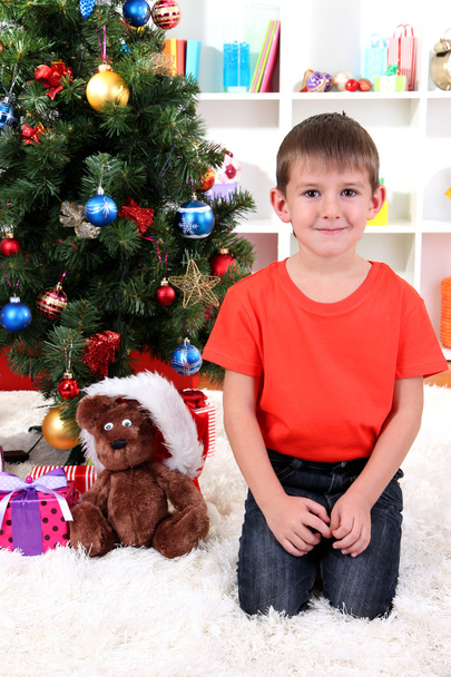 Little boy sits near Christmas tree - Foto, imagen