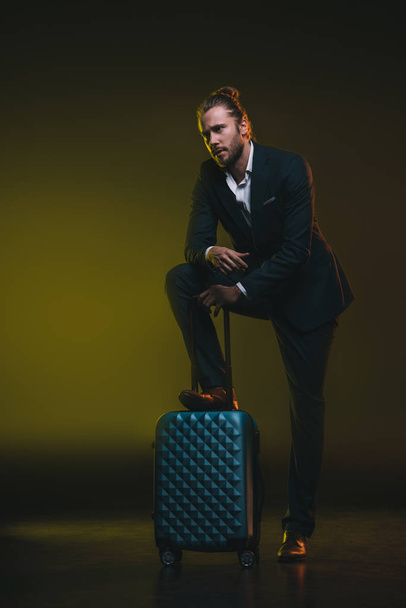 pensive man in suit leaning on suitcase - Foto, Bild