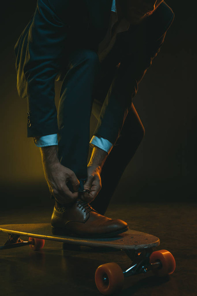 hombre de moda atando cordones de zapatos en el monopatín
 - Foto, Imagen