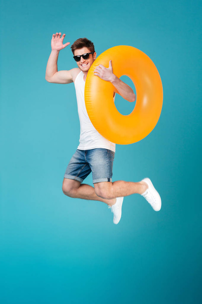 Happy excited man in sunglasses holding inflatable ring and jumping - Foto, immagini