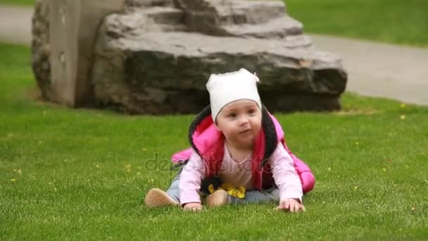 Cute smiling baby-girl crawling on a green grass in the city park. - 映像、動画