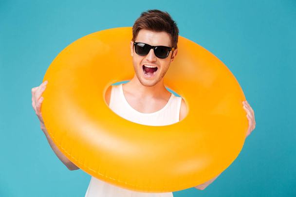 Portrait of a cheerful man in sunglasses holding inflatable ring - Foto, immagini