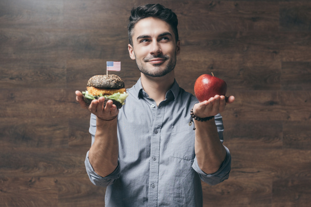 Hombre con hamburguesa y manzana
  - Foto, Imagen