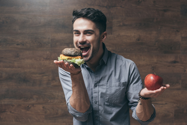 Man with hamburger and apple  - Φωτογραφία, εικόνα