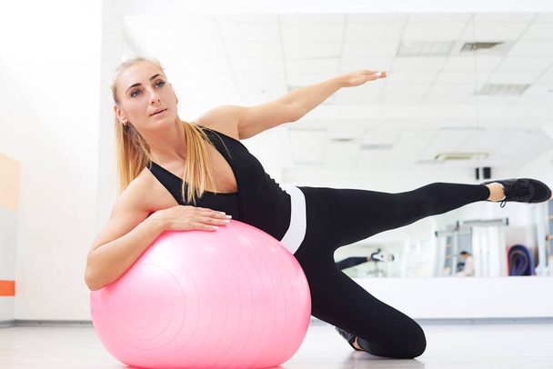 Mulher no fitball fazendo exercício de dobragem lateral no ginásio indoor
 - Foto, Imagem