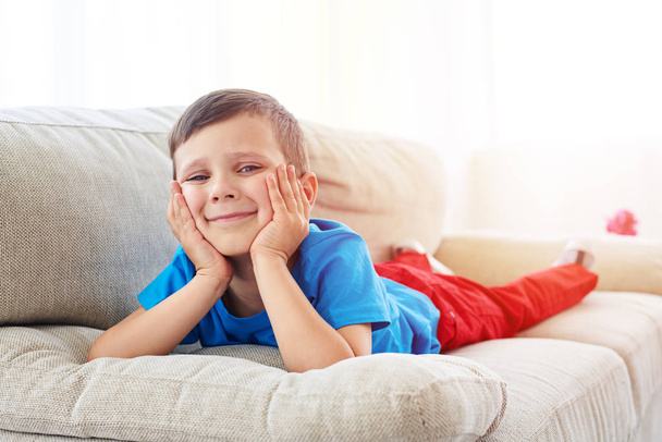 Curious small boy lying at living room on sofa - Foto, Imagen