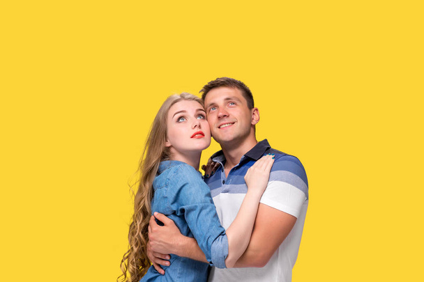 Portrait of a young couple standing against yellow background - Fotografie, Obrázek