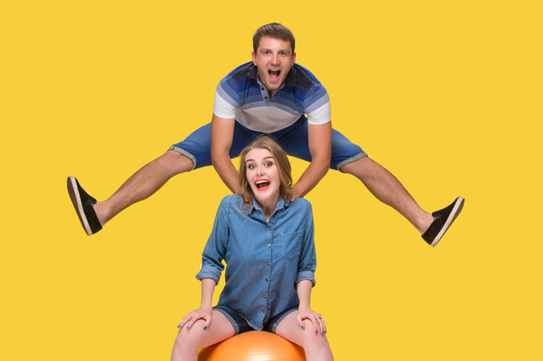Portrait of a young couple jumping against yellow background - Foto, imagen