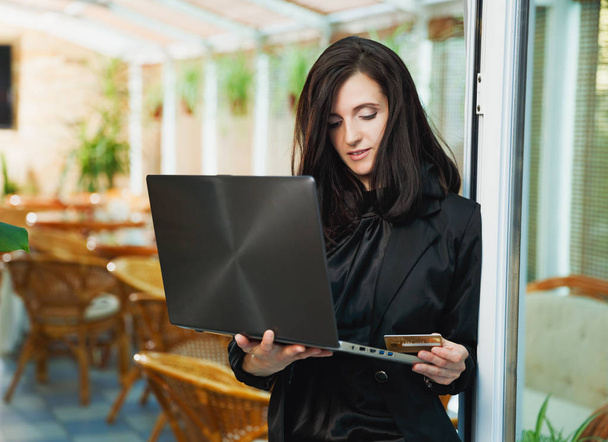 Ділова жінка стоїть в ресторані з ноутбуком і кредитним автомобілем
 - Фото, зображення