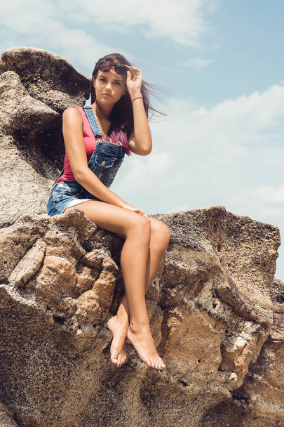 Girl in denim overall on the rock beach. - Fotografie, Obrázek