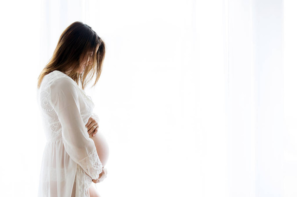 Portrait of young pregnant attractive woman, standing by the win - Foto, Imagem