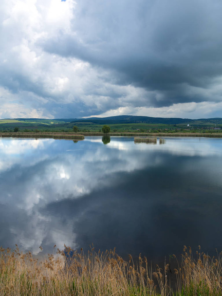 Panoramic view to lake Rotbav, tourist resort with hills in the background on a sunny spring day with cloudy blue sky Rotbav, Romania, Europe - Photo, Image
