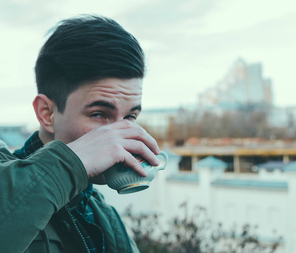 Man drinks coffee by the river - Фото, зображення