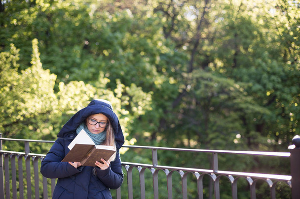 Onnellinen tyttö lukee kirjaa kaiteella
. - Valokuva, kuva