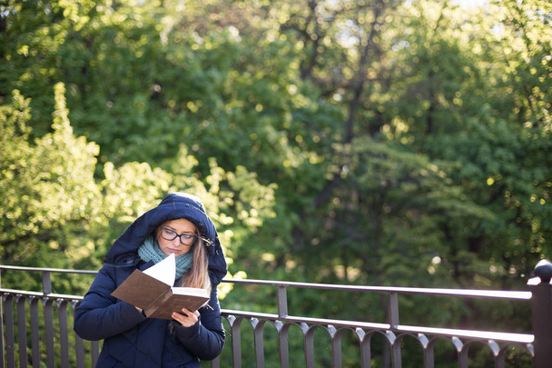 Happy girl reading a book at the railing. - Photo, image