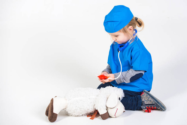 small boy in doctor uniform playing vet with toy animal - Foto, Imagen