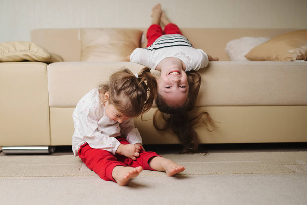 little cute girls on the couch upside down - 写真・画像