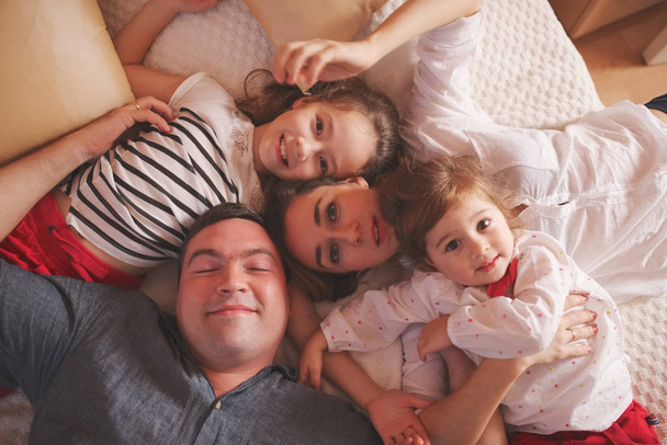 young family lying in bed at home - Photo, Image