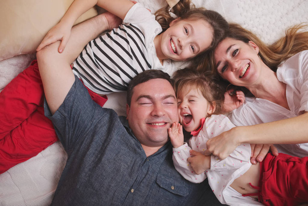 young family lying in bed at home - Foto, Bild