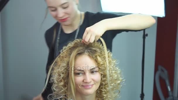 Szép, szőke hajú lány, hosszú haj, fodrász teszi afrikai fürtök szépségszalon. Professzionális hajápolás és frizura létrehozása. - Felvétel, videó