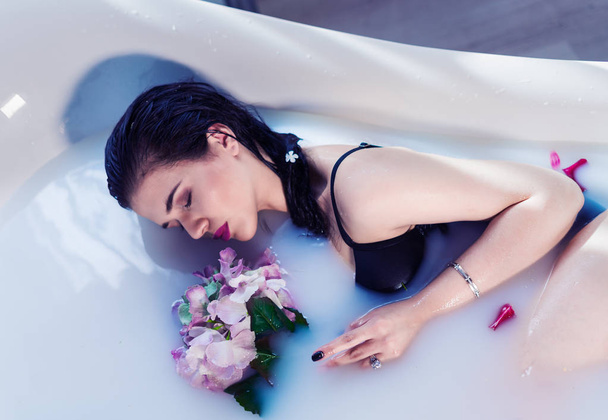 セクシーなブルネットの女性の花とお風呂でリラックス - 写真・画像