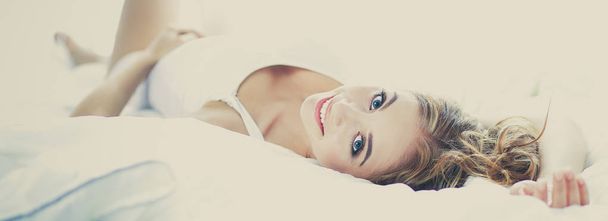 portrait of an attractive young woman lying on a bed . - Foto, Bild