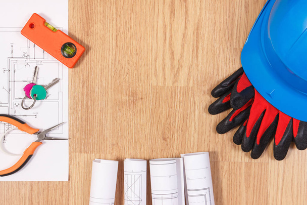 Ключи от дома с электрическими чертежами, защитный синий шлем с перчатками и оранжевые рабочие инструменты, концепция строительства дома
 - Фото, изображение