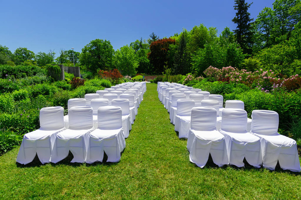 geweldig uitzicht op de witte ingerichte stoelen in de botanische tuin een huwelijk ceremonie gebeurtenis voorbereid - Foto, afbeelding