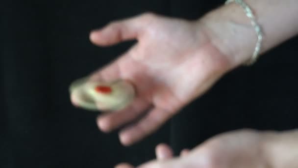 der Trick mit dem Handspinner auf schwarzem Hintergrund, der junge Mann wirft den Spinner mit einer Hand in die andere - Filmmaterial, Video