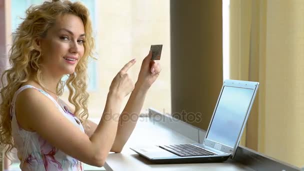 保持している美しい女性手にクレジット カードとクレジット カードに彼の指を示しています - 映像、動画
