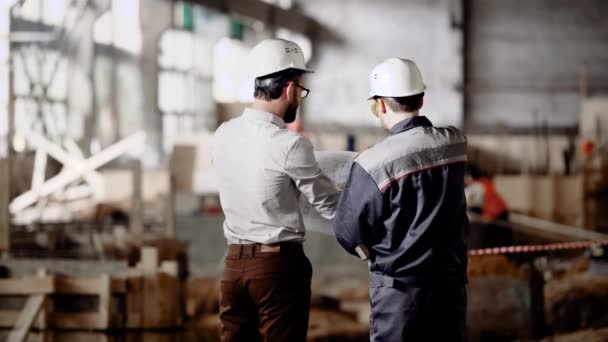 Architect and worker at the construction site. Construction of an industrial plant. The chief architect reviews the plan and decides on further work. - Footage, Video