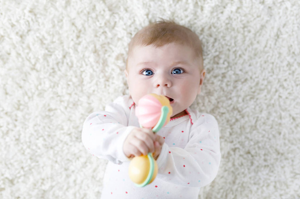 Cute baby girl playing with colorful pastel vintage rattle toy - Foto, afbeelding
