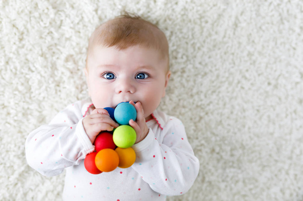 Schattige babymeisje spelen met kleurrijke houten rammelaar speelgoed - Foto, afbeelding