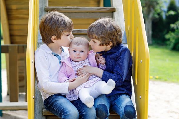zwei kleine glückliche Jungen mit neugeborenen Mädchen, süße Schwester. - Foto, Bild