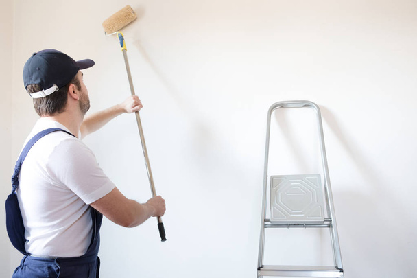 Professional painter worker is painting one wall - Φωτογραφία, εικόνα