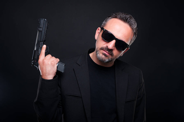 Killer man with pistol on dark background - Photo, Image