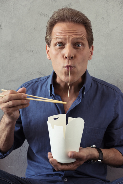 mature man fooling around with noodles - Photo, Image