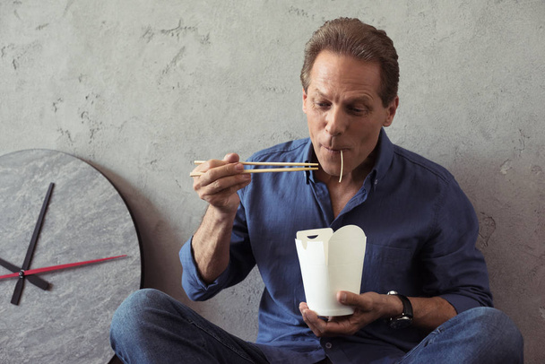 middle aged man eating noodles - Фото, изображение