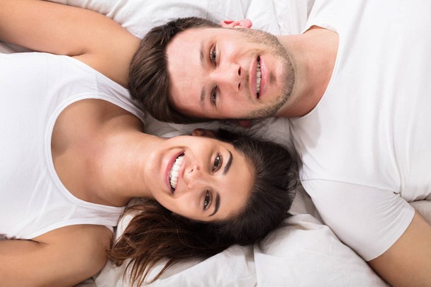 couple lying on bed and looking at camera - Фото, изображение