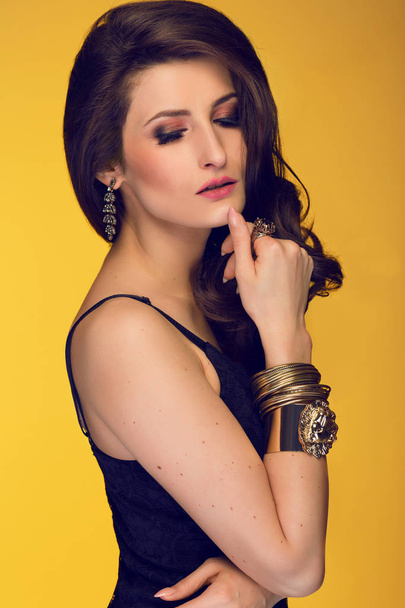 Sensual beautiful brunette woman posing in black dress and gold  - Foto, imagen