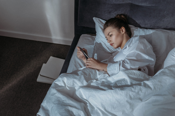 woman using phone in bed - Photo, Image