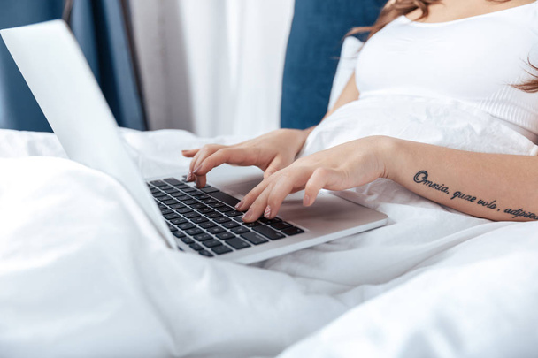 Γυναίκα που χρησιμοποιεί φορητό υπολογιστή στο κρεβάτι - Φωτογραφία, εικόνα
