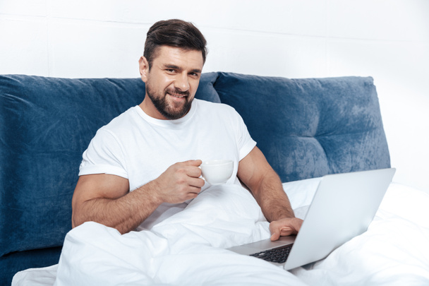 man working on laptop in bed - Φωτογραφία, εικόνα