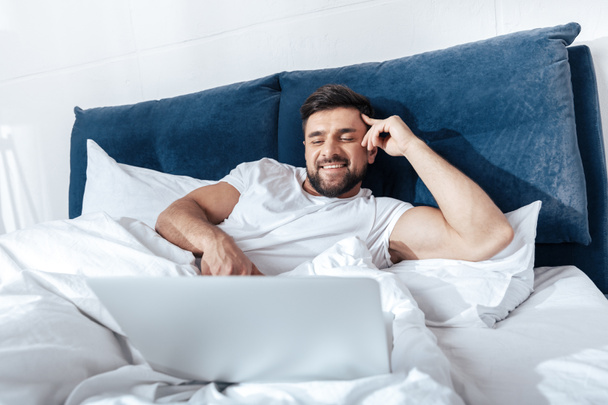 man using laptop in bed - Photo, image