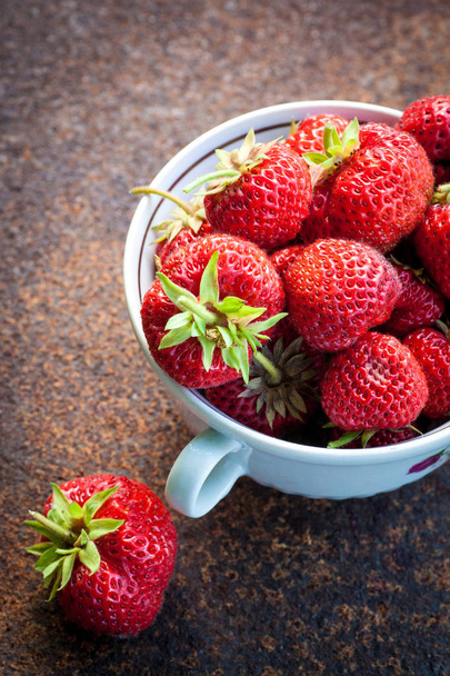 Fresh strawberries in bowl of ceramics on old metal background. Natural food. - Фото, изображение