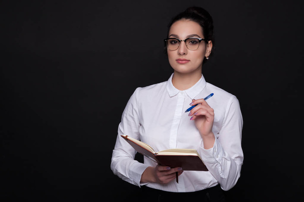 Mulher de negócios em óculos com um bloco de notas em um fundo preto
 - Foto, Imagem
