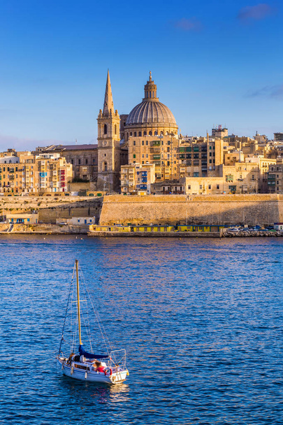 La Valeta, Malta - Catedral de San Pablo en hora dorada en la capital de Malta La Valeta con velero y hermoso cielo azul
 - Foto, Imagen
