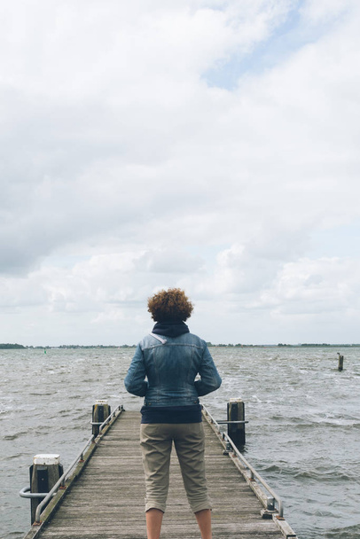 Back view of woman with casual clothing standing on wooden pier  - Fotó, kép